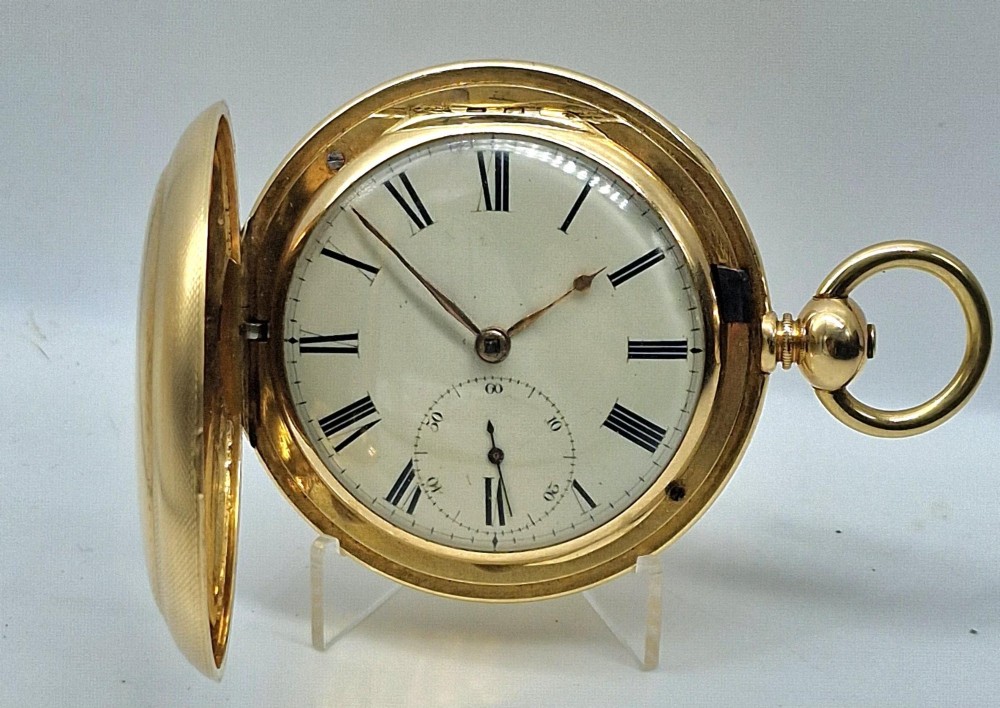 A 14k yellow gold full hunter pocket watch displayed with its cover open to show a white enamel dial with black Roman numerals and a subsidiary seconds sub-dial.