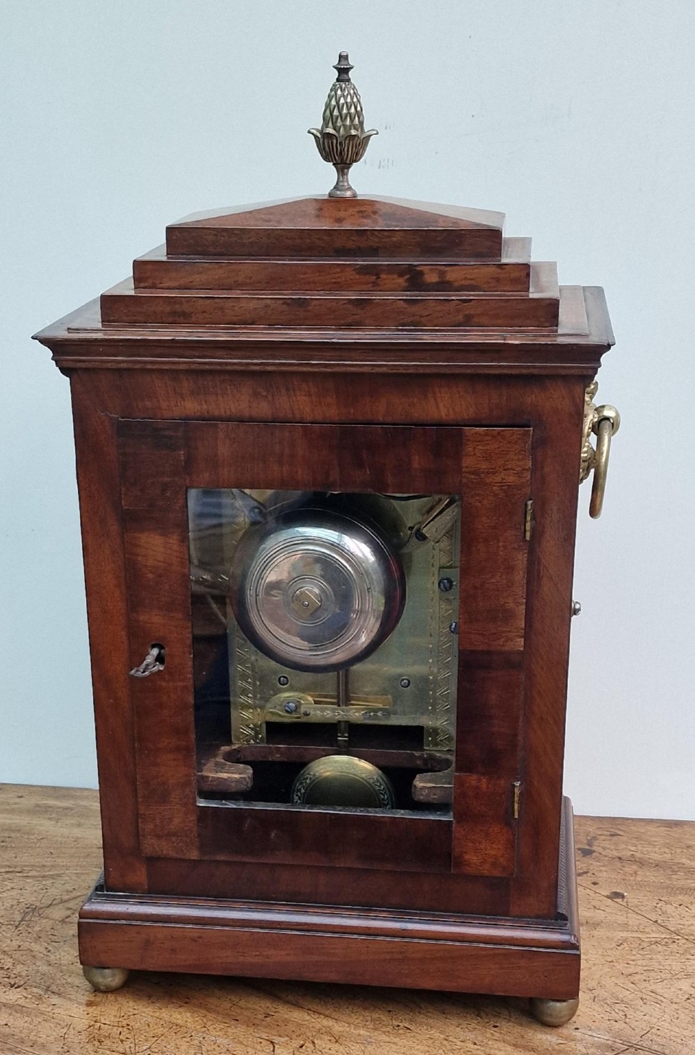A Regency mahogany bracket clock featuring a white circular dial signed Thomas Jackson London, framed by brass stringing, lion head side handles, and a pineapple finial. View II