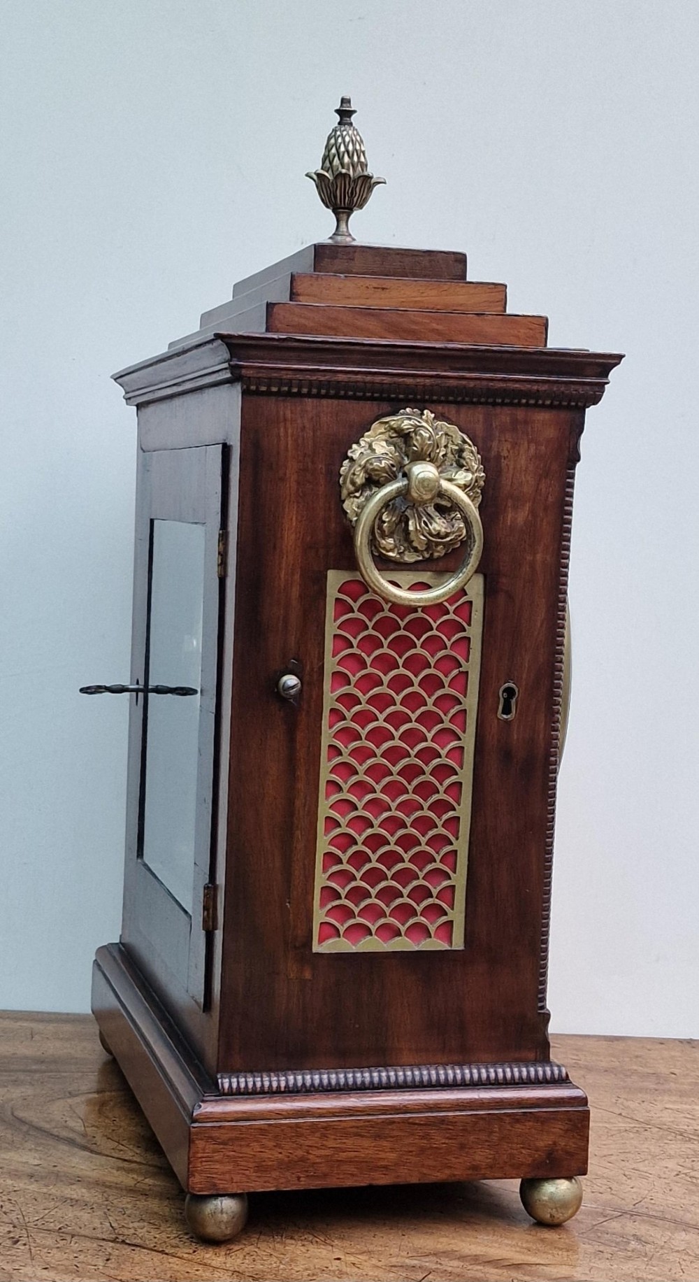A Regency mahogany bracket clock featuring a white circular dial signed Thomas Jackson London, framed by brass stringing, lion head side handles, and a pineapple finial. View VI