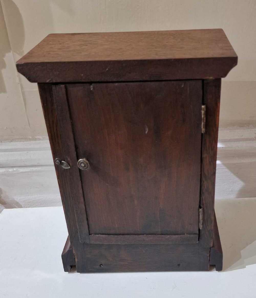 An upright wooden mantel clock featuring a brass-rimmed dial marked with the RAF crest and Roman numerals, set above an oval floral marquetry inlay on a stepped base. View II
