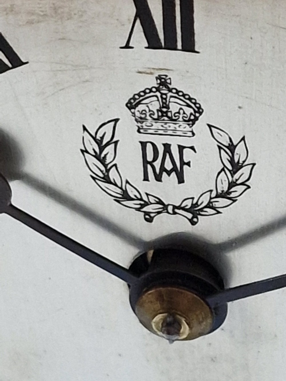 An upright wooden mantel clock featuring a brass-rimmed dial marked with the RAF crest and Roman numerals, set above an oval floral marquetry inlay on a stepped base. View III