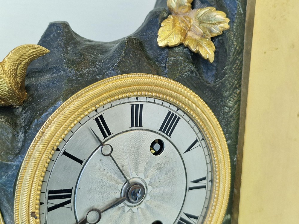 A 19th-century French gilt bronze and patinated bronze mantel clock featuring a seated gilded child figure atop a dark rock-form casing with Roman numerals. View III