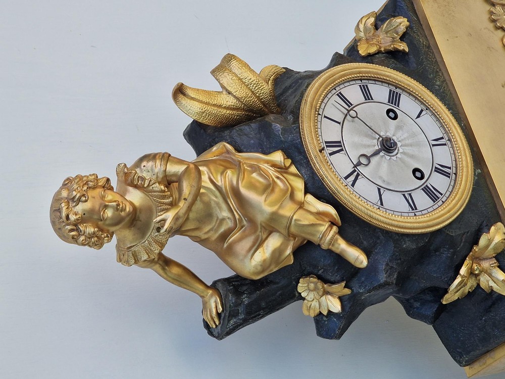 A 19th-century French gilt bronze and patinated bronze mantel clock featuring a seated gilded child figure atop a dark rock-form casing with Roman numerals. View VII