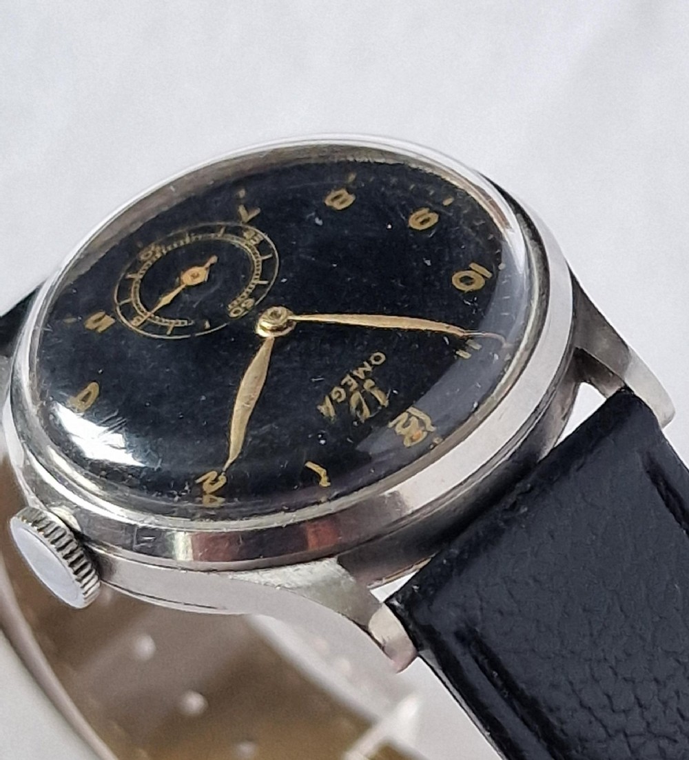 A vintage 1944 Omega wristwatch featuring a circular stainless steel case, black dial with Arabic numerals, sub-seconds dial, and a black leather strap. View VII