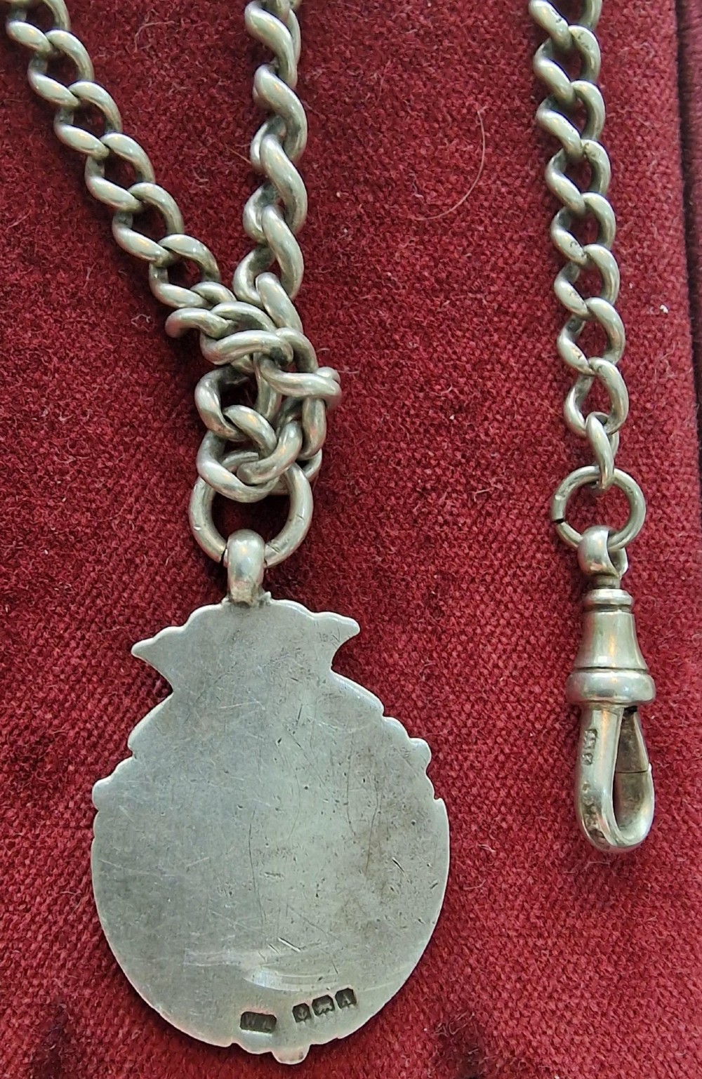 An antique silver pocket watch chain featuring curb links, a swivel clasp, a bolt ring, and a suspended crown-topped shield fob. View II