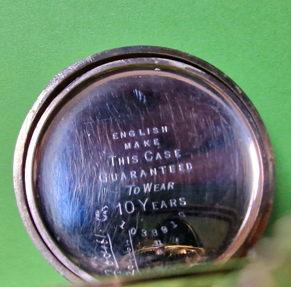 An open-face gold-toned pocket watch featuring a white enamel dial with black Arabic numerals, blued steel hands, and a subsidiary seconds sub-dial at six oclock. View II