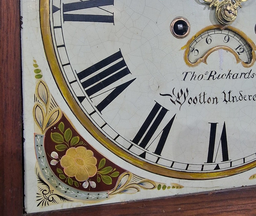 An antique Georgian flame mahogany longcase clock with three brass finials, an arched hood, fluted columns, and a painted dial displaying a moonphase mechanism. View III