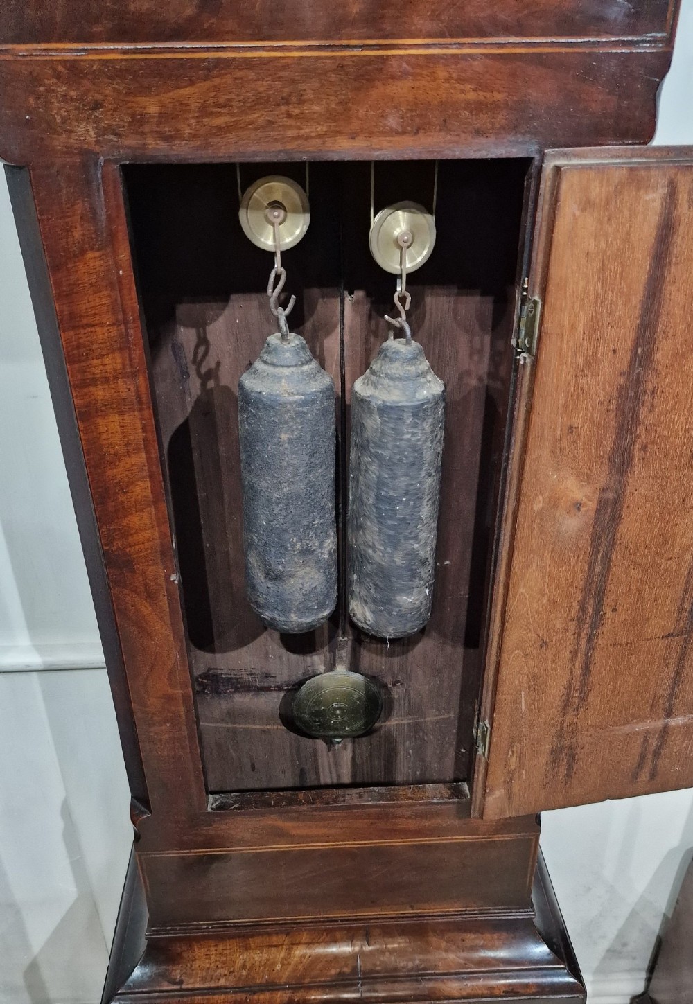 An antique Georgian flame mahogany longcase clock with three brass finials, an arched hood, fluted columns, and a painted dial displaying a moonphase mechanism. View IX