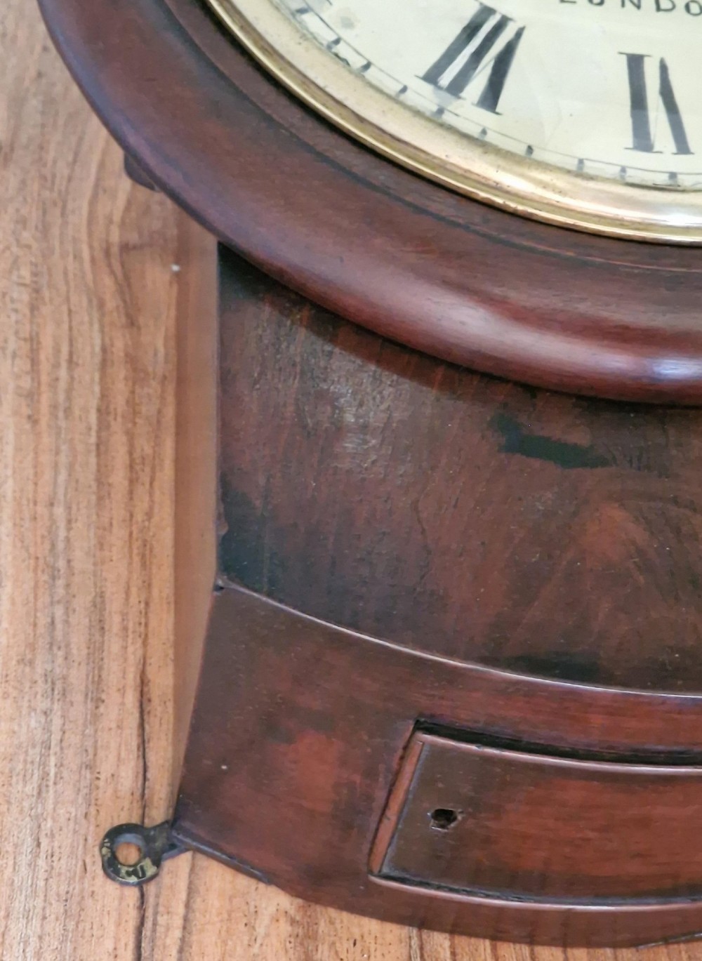 A small mahogany fusee wall clock featuring an eight-inch dial with Roman numerals, a brass bezel, and a lower wooden drop case. View II