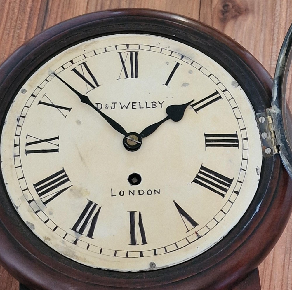 A small mahogany fusee wall clock featuring an eight-inch dial with Roman numerals, a brass bezel, and a lower wooden drop case. View IV