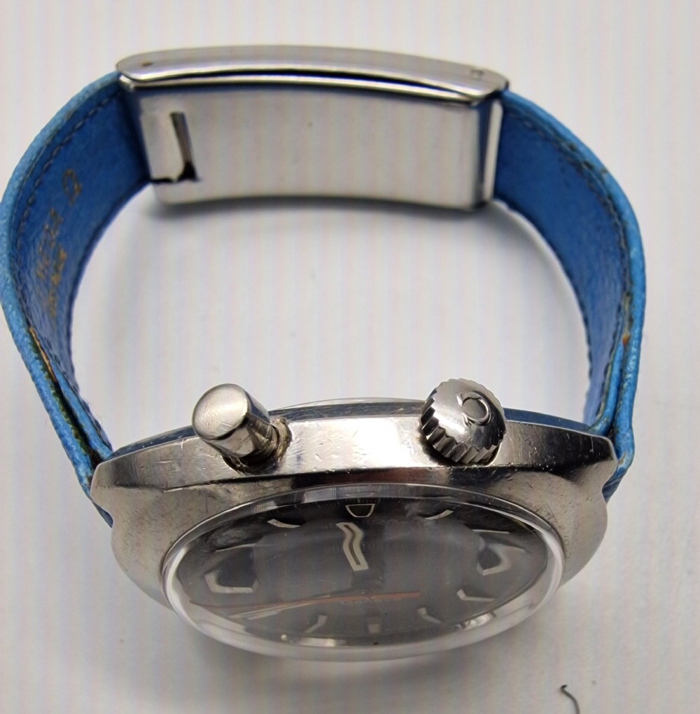 A 1969 Omega Chronostop stainless steel wristwatch featuring a dark dial, an orange seconds hand, and a bright blue leather strap. View IV