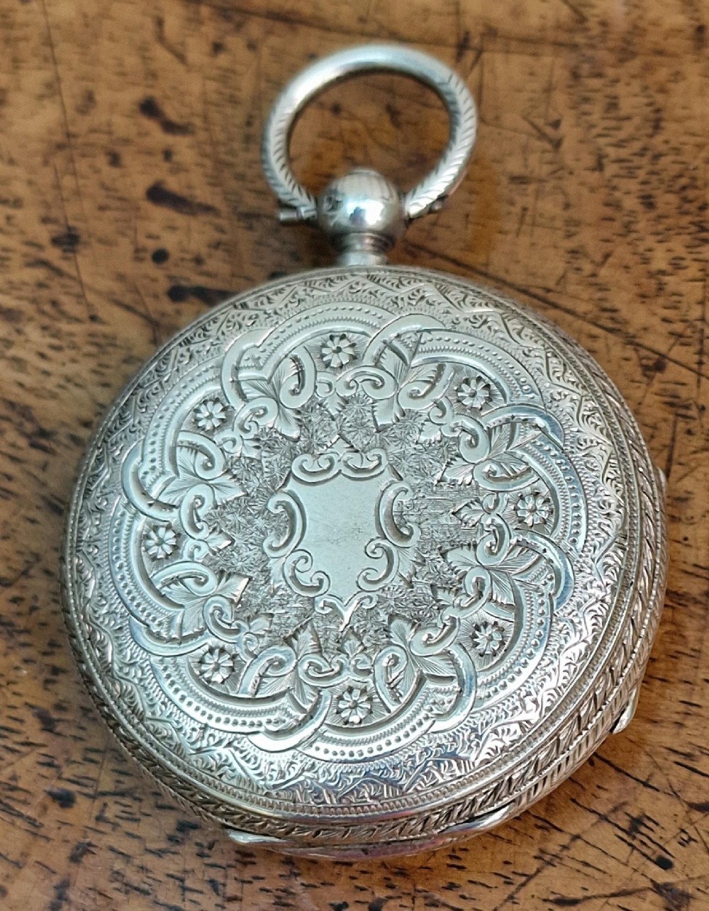 A Victorian silver open-face pocket watch featuring a white enamel dial with Roman numerals alongside an accompanying brass winding key. View II