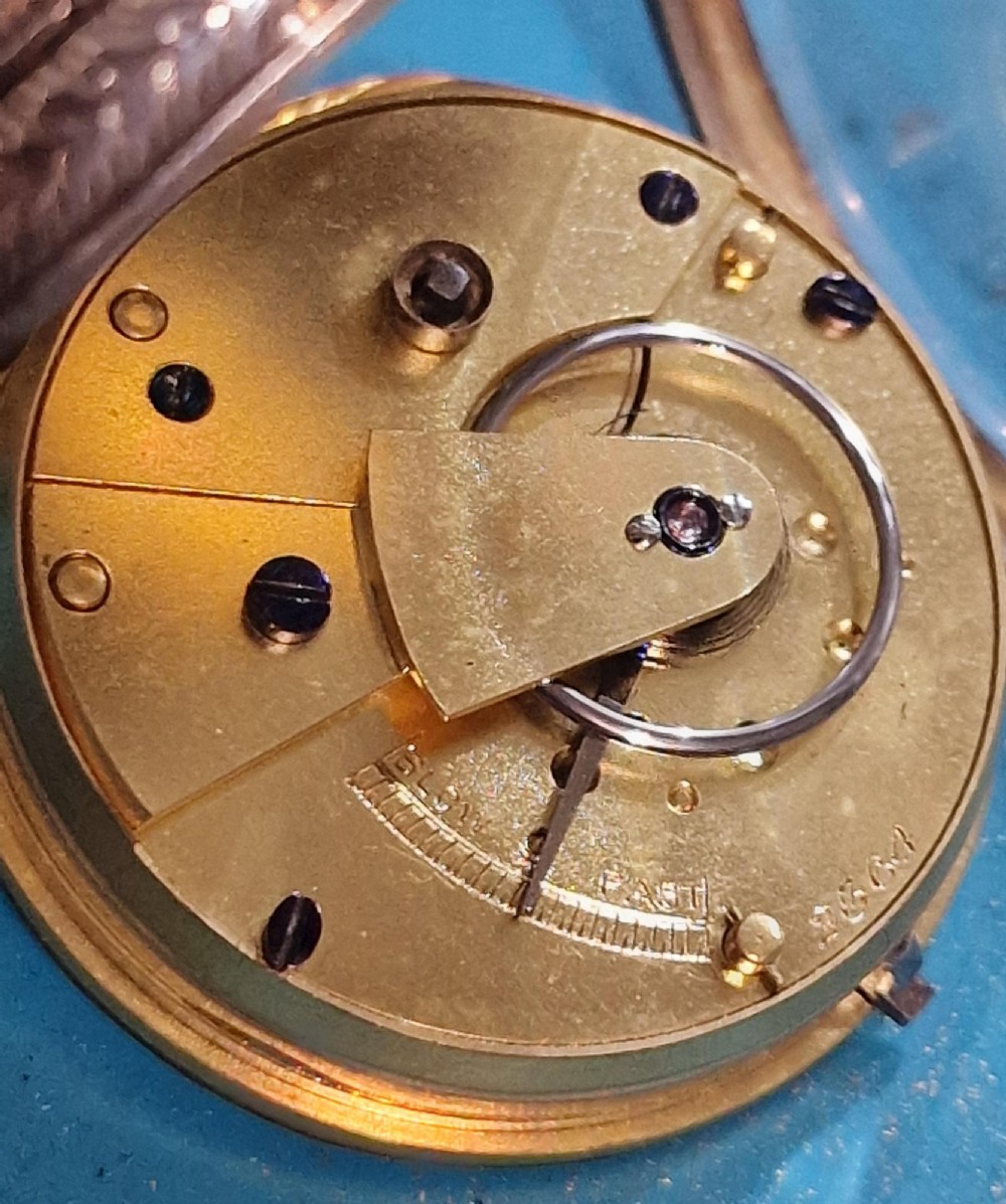 A Victorian silver open-face pocket watch featuring a white enamel dial with Roman numerals alongside an accompanying brass winding key. View III