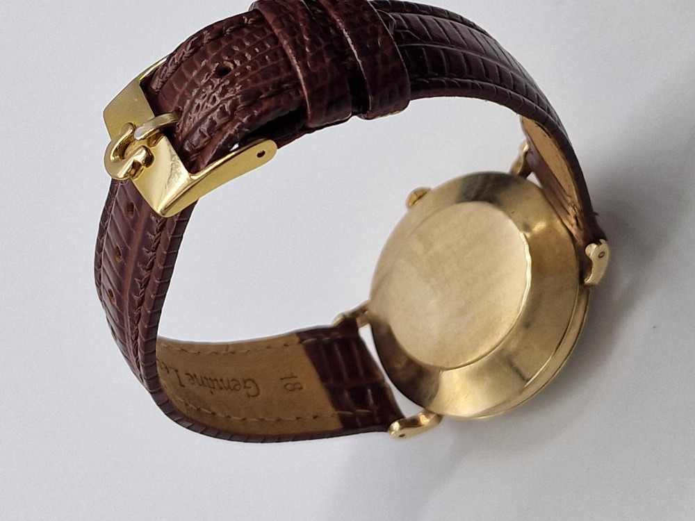 A 1950s vintage Omega automatic wristwatch crafted with a 9K gold case and brown leather strap, set inside a red presentation box. View III