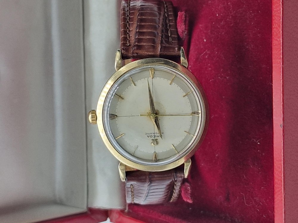 A 1950s vintage Omega automatic wristwatch crafted with a 9K gold case and brown leather strap, set inside a red presentation box. View V