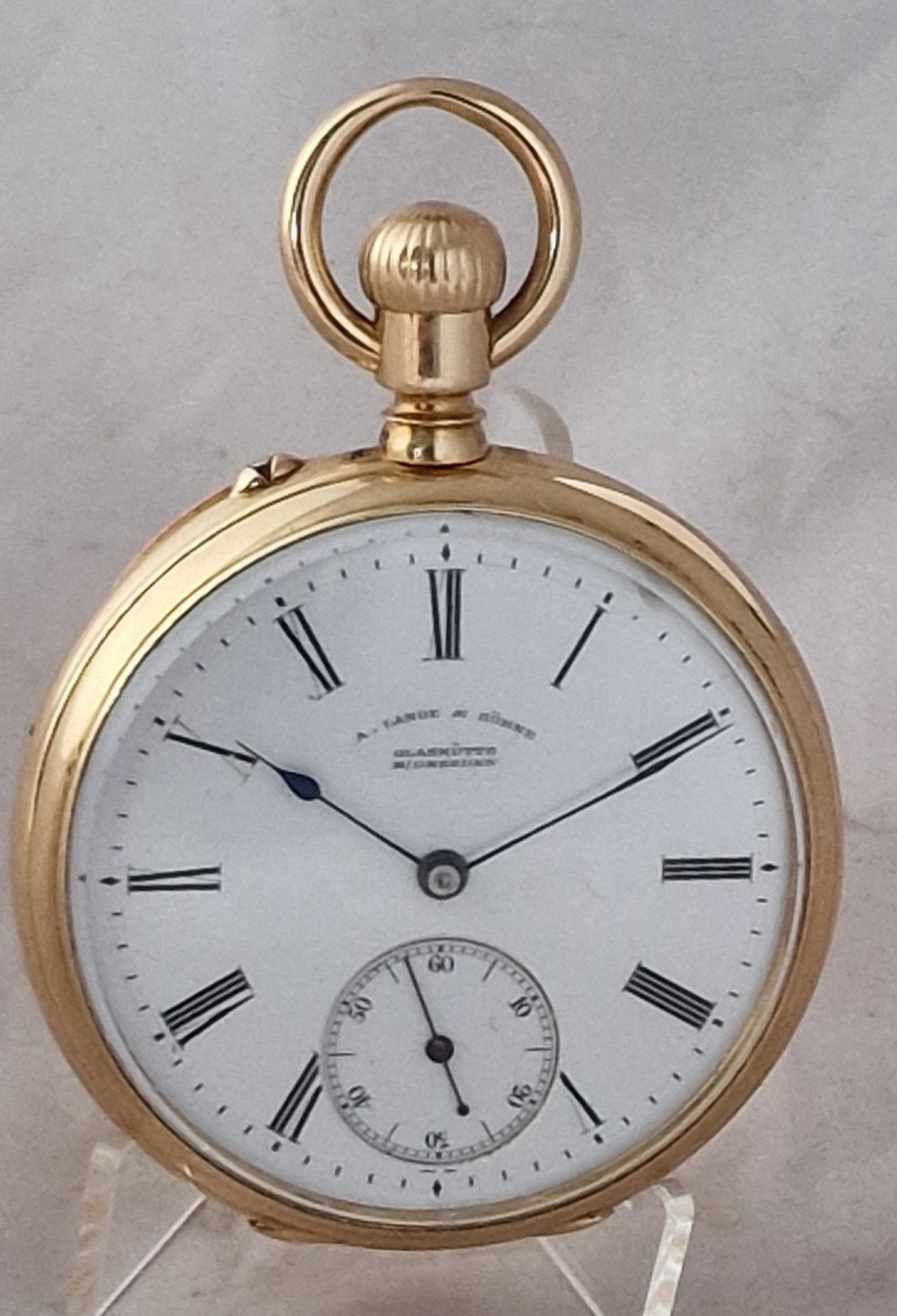 An open-face 18ct yellow gold pocket watch featuring a white enamel dial with black Roman numerals and a subsidiary seconds dial.