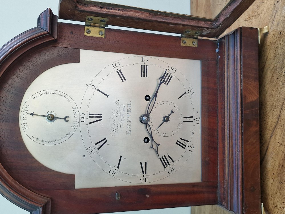 A Georgian mahogany bracket clock featuring an arched top with a brass carrying handle, silvered engraved dial with Roman numerals, and brass bracket feet. View II