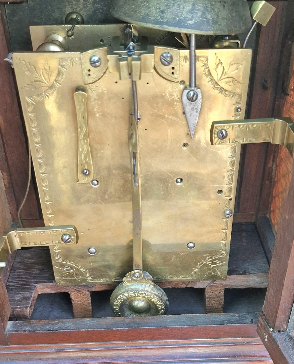 A Georgian mahogany bracket clock featuring an arched top with a brass carrying handle, silvered engraved dial with Roman numerals, and brass bracket feet. View VI