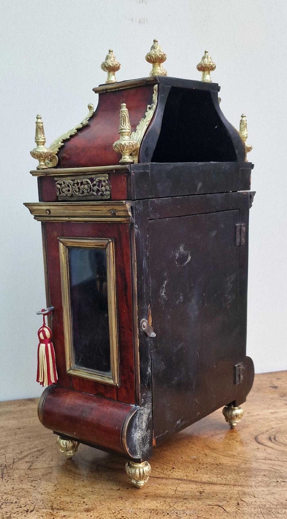 A red tortoiseshell and gilt bronze mantel clock featuring enamel Roman numeral cartouches and cast finials. View III