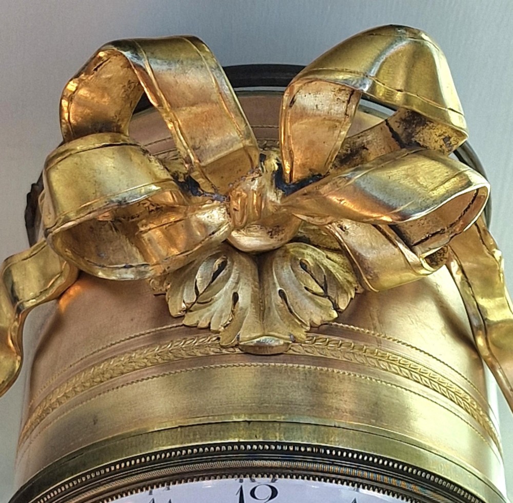 A French Louis XVI style gilt bronze and white marble mantel clock featuring an enamel dial topped with a ribbon crest motif and supported on turned feet. View VI