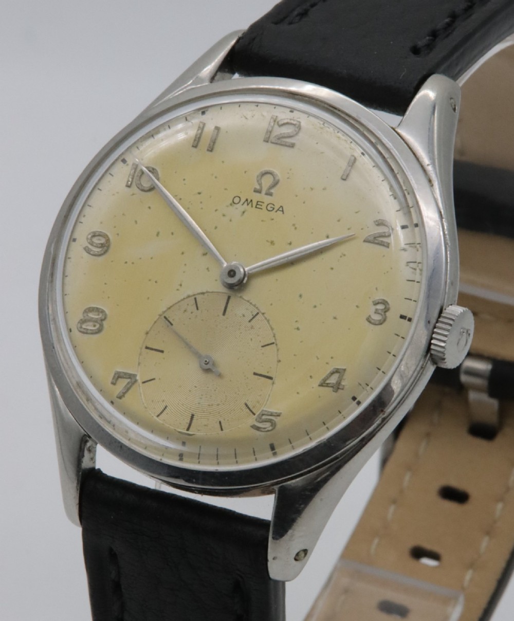 A 1947 Omega wristwatch featuring a circular stainless steel case, a patinated cream dial with Arabic numerals, a sub-seconds dial, and a black leather strap. View II