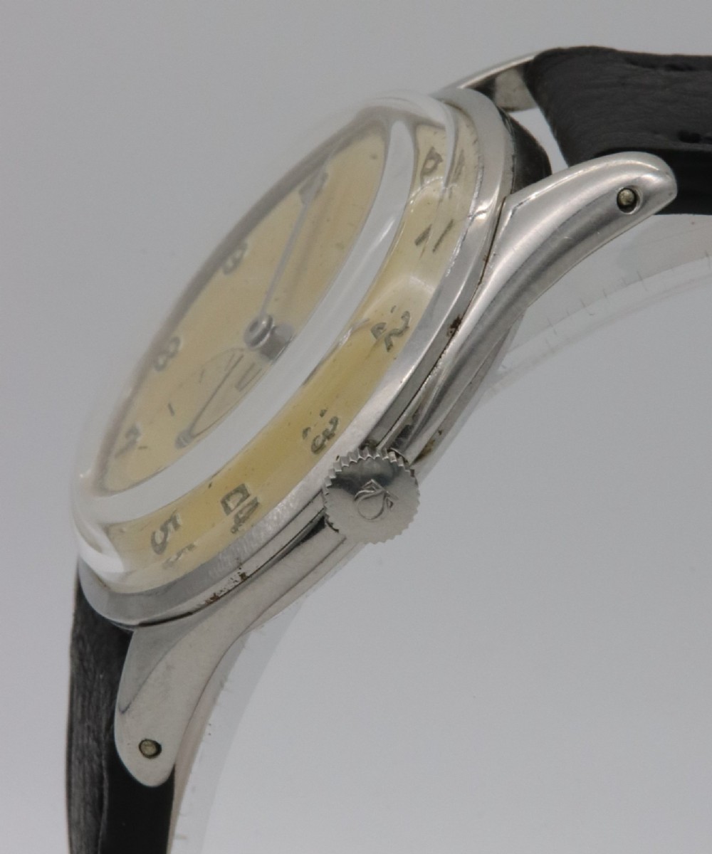A 1947 Omega wristwatch featuring a circular stainless steel case, a patinated cream dial with Arabic numerals, a sub-seconds dial, and a black leather strap. View III