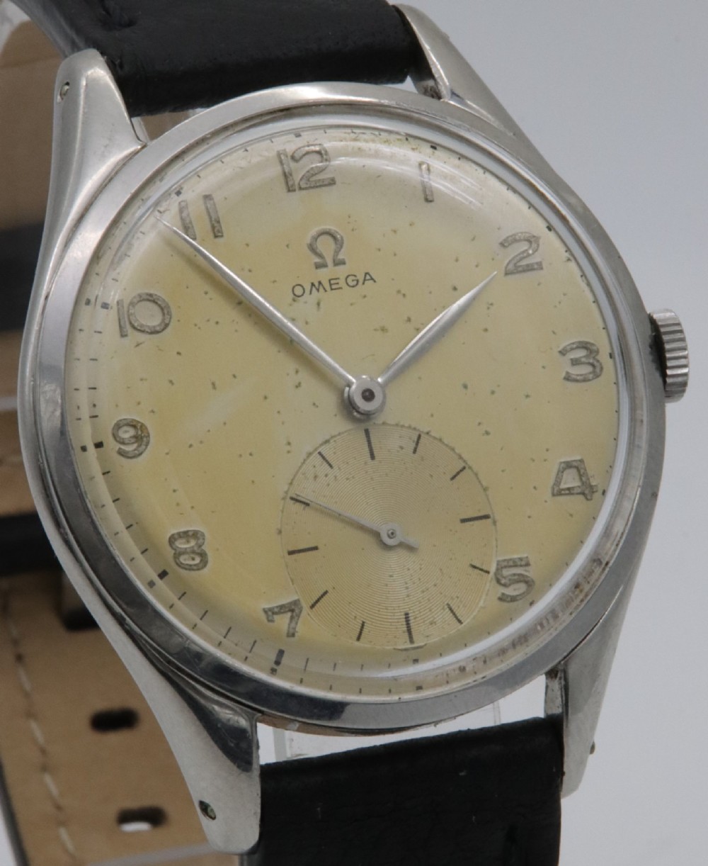 A 1947 Omega wristwatch featuring a circular stainless steel case, a patinated cream dial with Arabic numerals, a sub-seconds dial, and a black leather strap. View IV