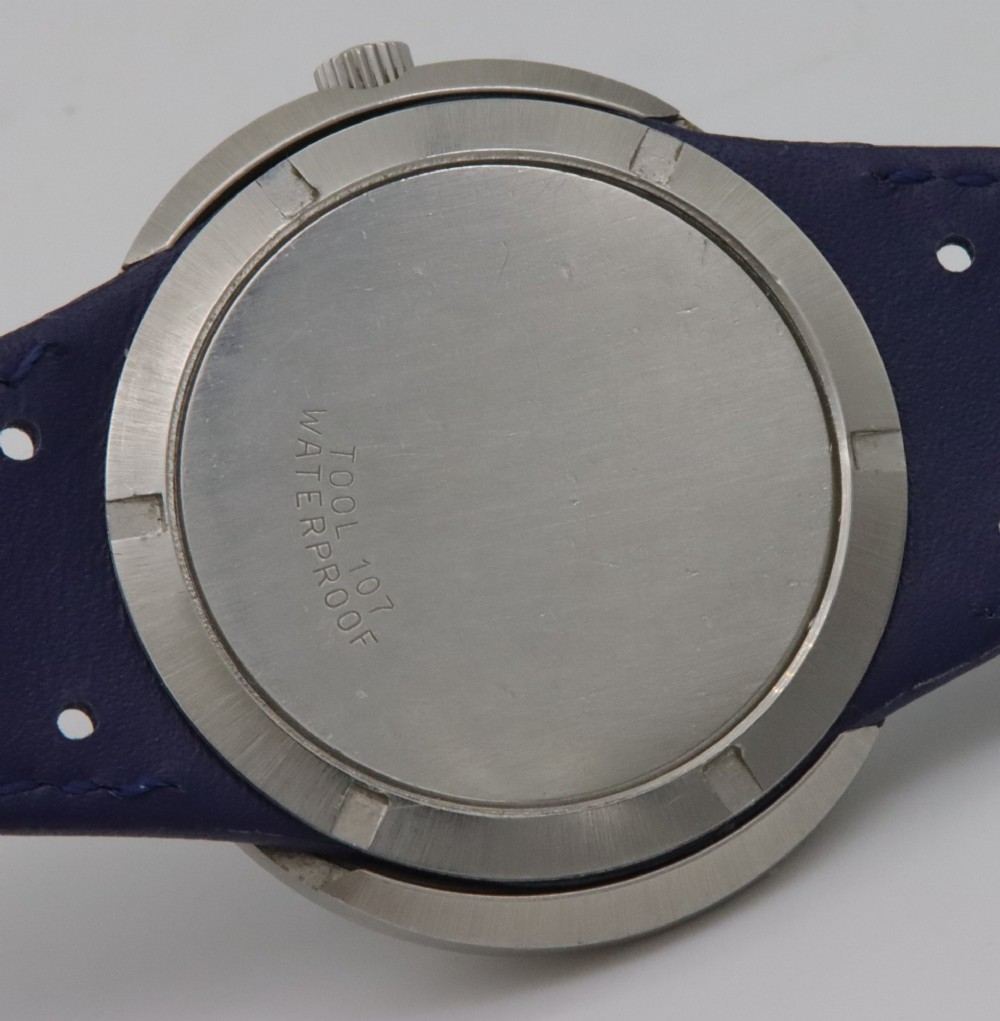 A 1969 Omega Geneve Dynamic stainless steel wristwatch with an elliptical case, dark navy dial, light blue seconds hand, and a perforated navy leather strap. View VII