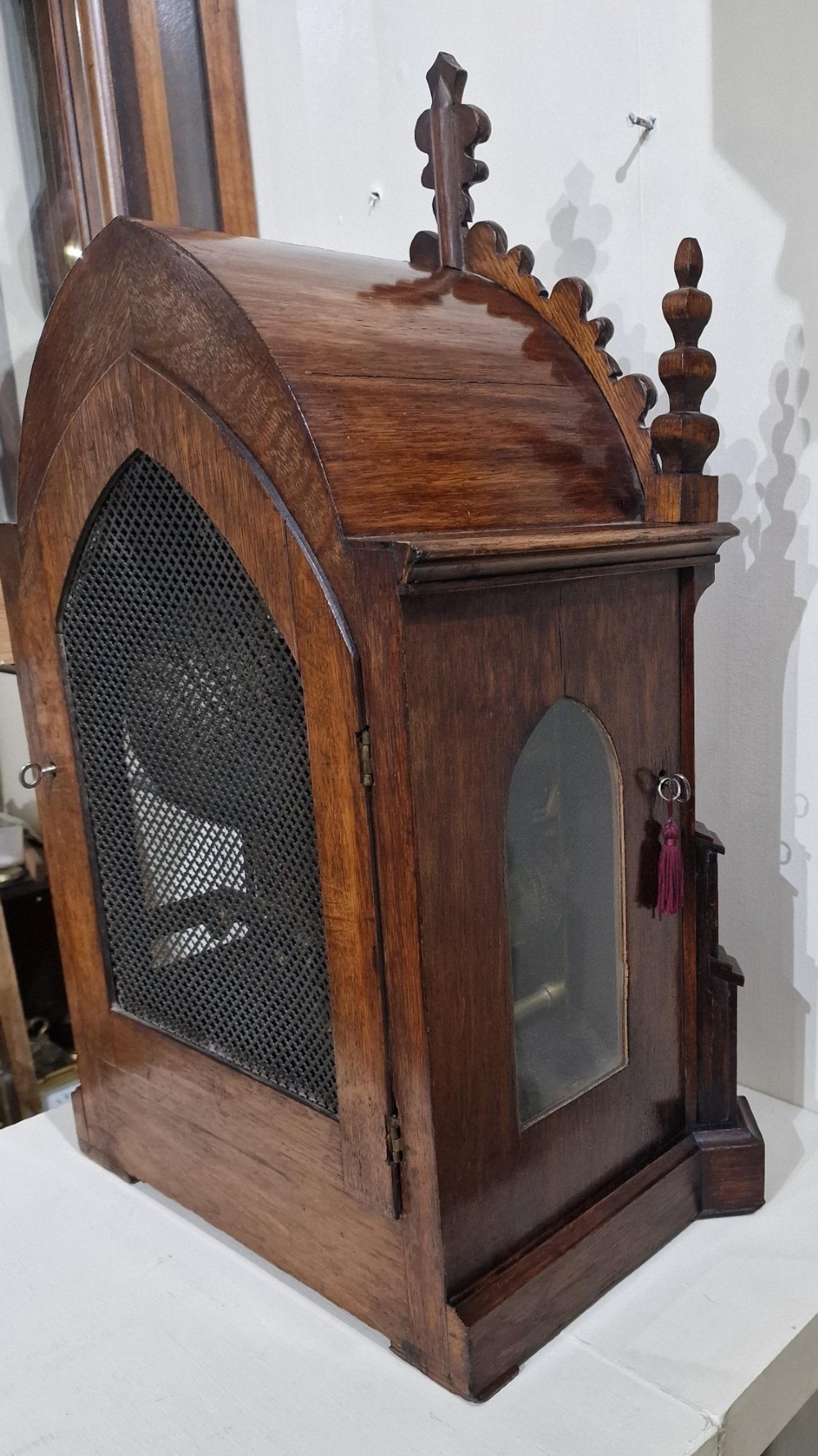A carved oak Gothic Revival bracket clock featuring pointed arch cresting, turned finials, blind tracery details, and an engraved brass dial with Roman numerals. View III