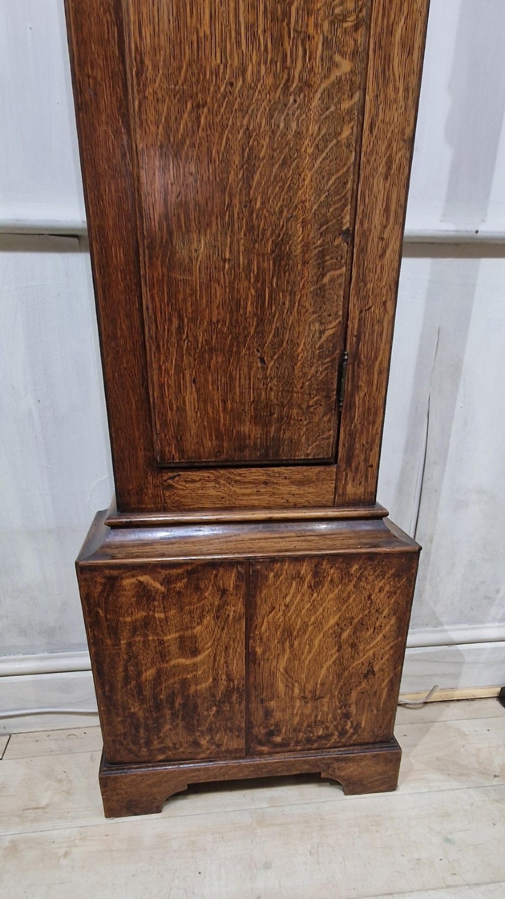 A Georgian oak longcase clock featuring a swan-neck pediment with brass eagle finials and an arched brass dial. View II
