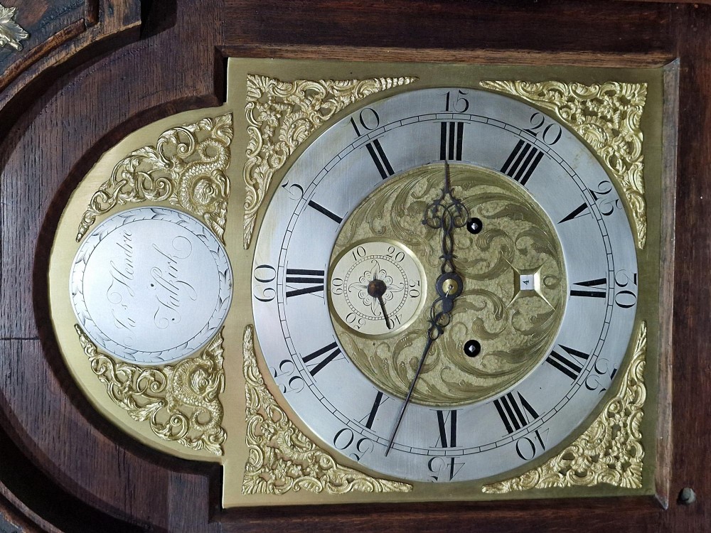 A Georgian oak longcase clock featuring a swan-neck pediment with brass eagle finials and an arched brass dial. View IV