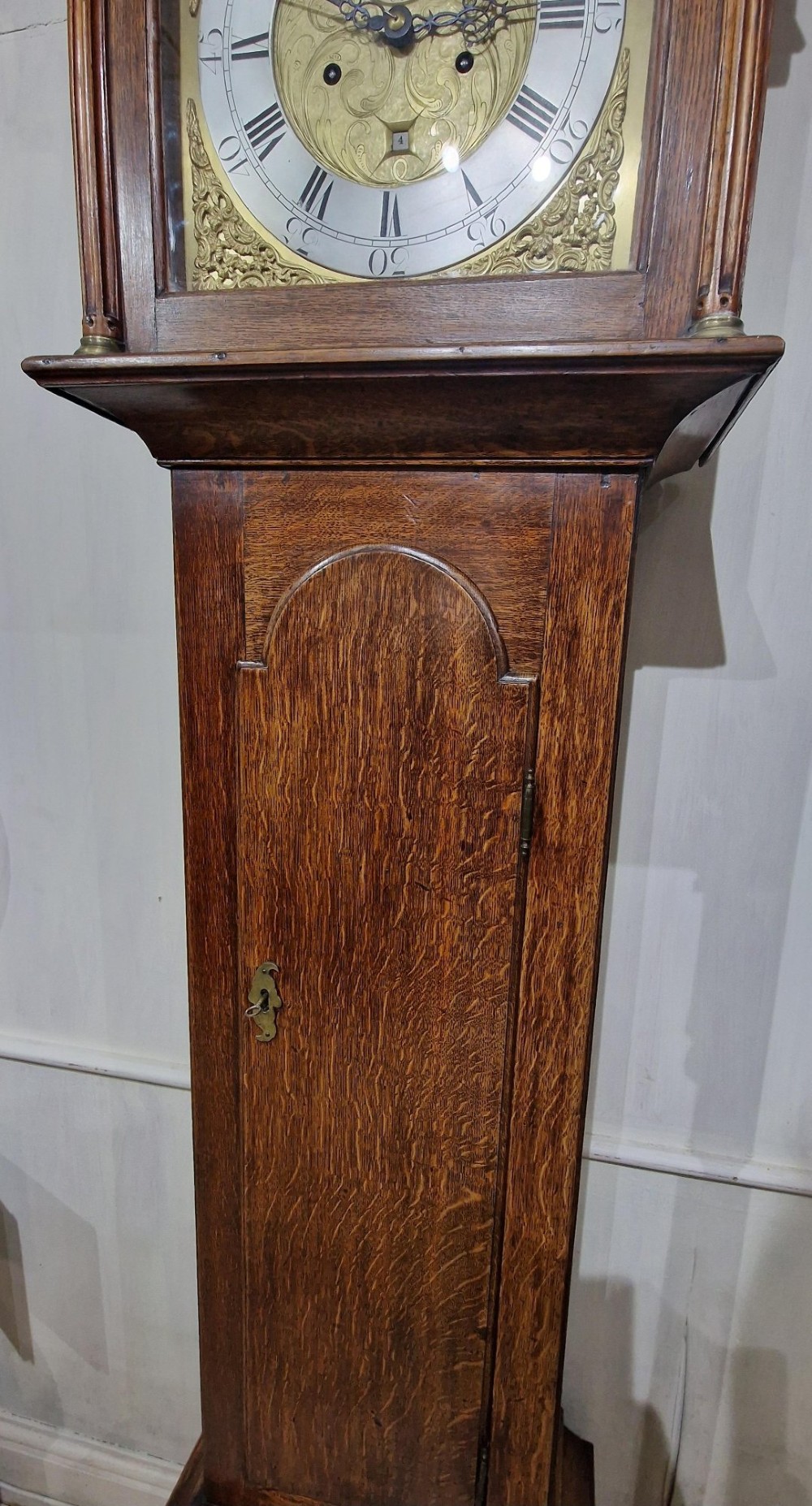 A Georgian oak longcase clock featuring a swan-neck pediment with brass eagle finials and an arched brass dial. View VII
