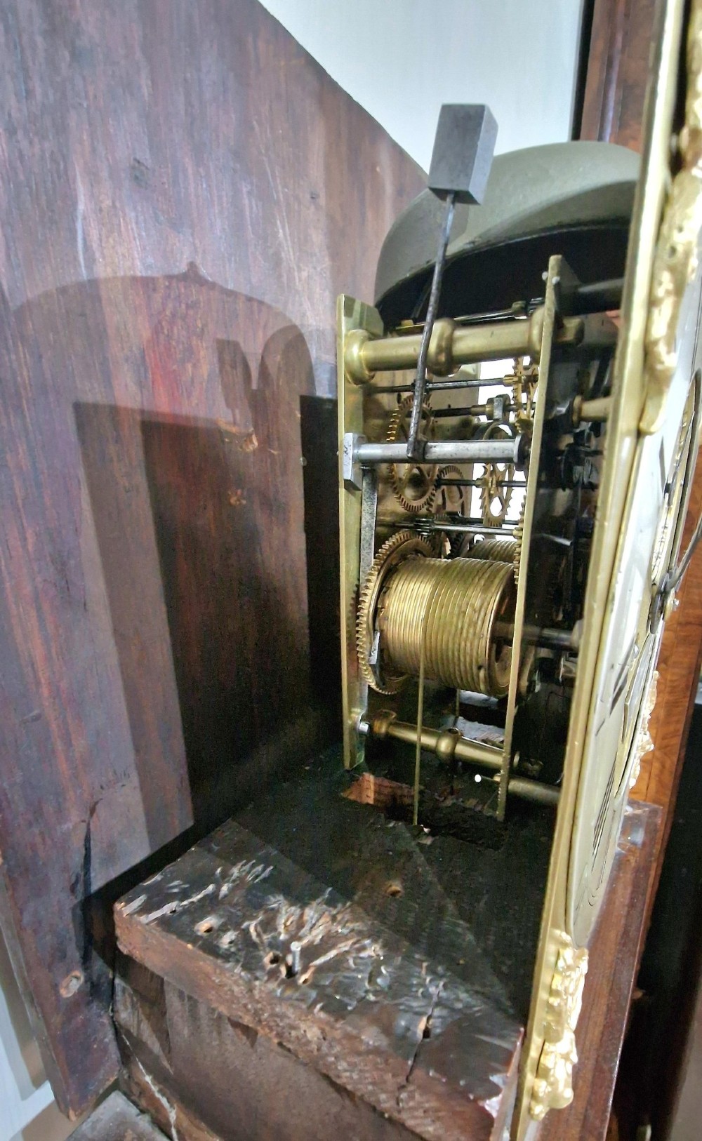 A Georgian mahogany grandmother clock featuring a swan-neck pediment, brass rosettes, an engraved brass and silvered dial, and an inlaid wooden trunk case. View V