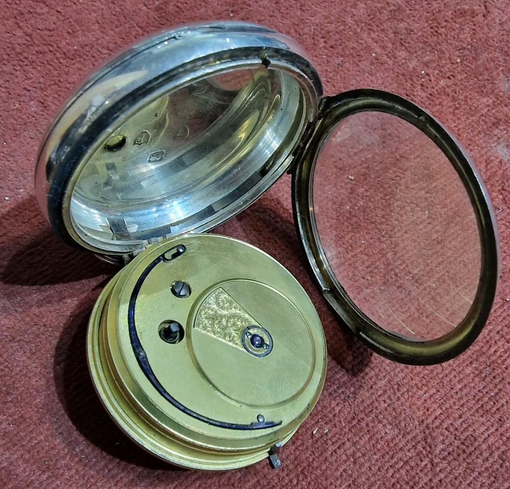 An antique silver open face fusee pocket watch featuring a white enamel dial with black Roman numerals, a subsidiary seconds dial, and an accompanying winding key. View V