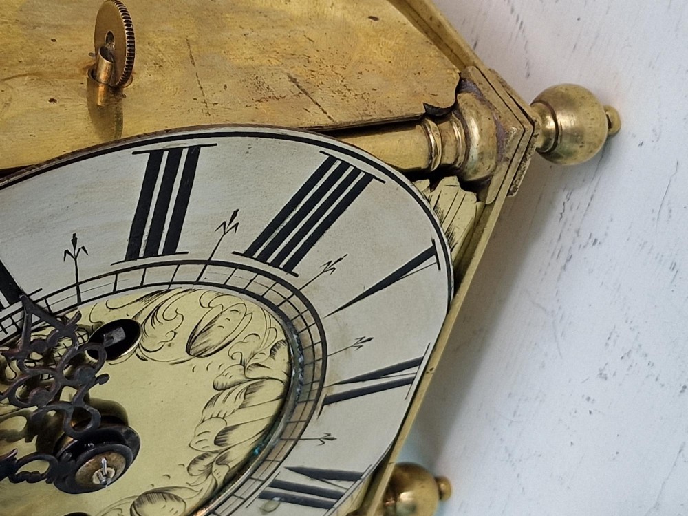 A 17th-century English brass lantern clock featuring an overhead bell, decorative pierced frets, ball feet, and an engraved dial centre signed Thomas Langley London. View III