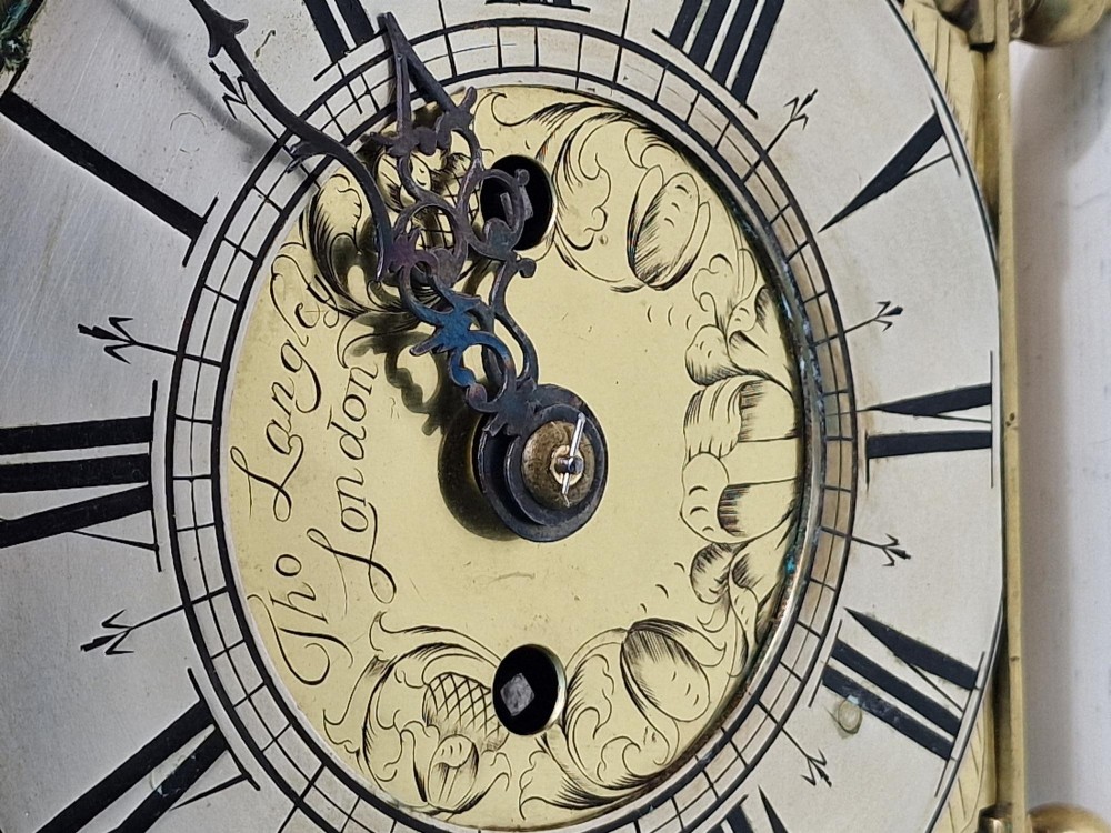 A 17th-century English brass lantern clock featuring an overhead bell, decorative pierced frets, ball feet, and an engraved dial centre signed Thomas Langley London. View IV