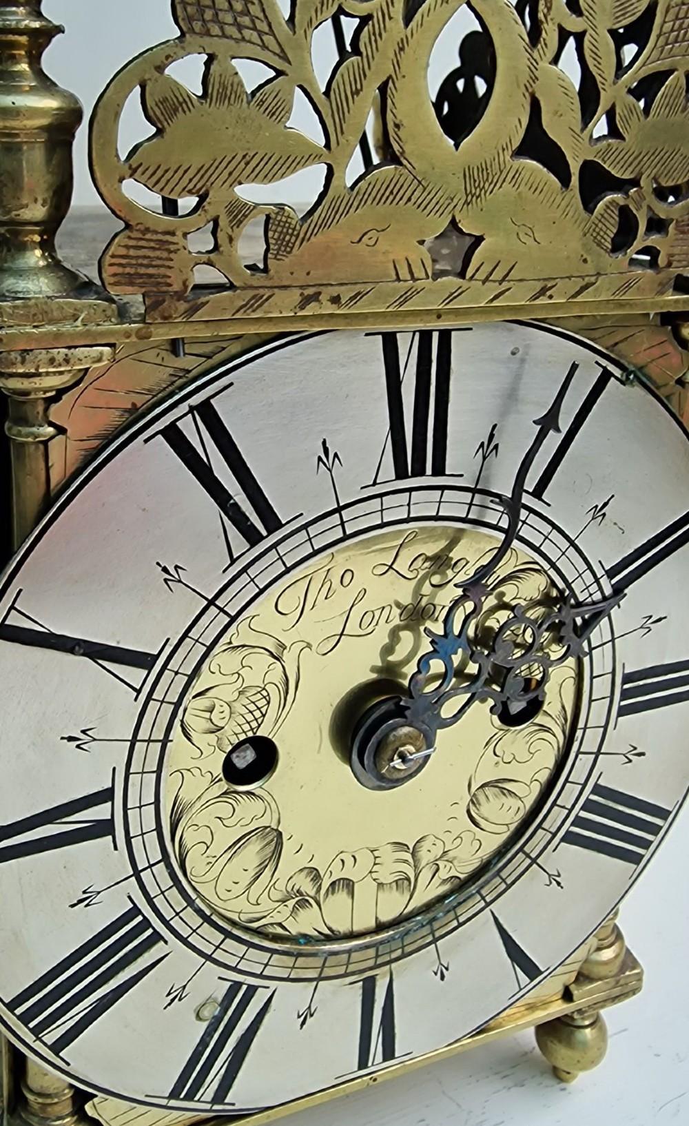 A 17th-century English brass lantern clock featuring an overhead bell, decorative pierced frets, ball feet, and an engraved dial centre signed Thomas Langley London. View IX
