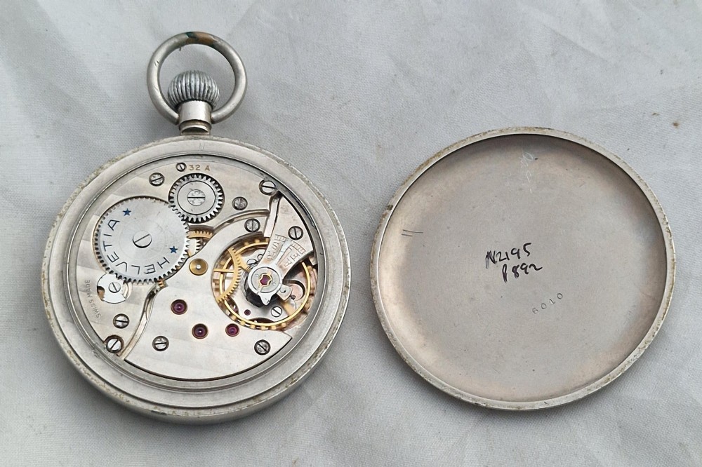 A Second World War Helvetia military pocket watch featuring a black dial with luminous Arabic numerals and a silver-toned metal case. View III