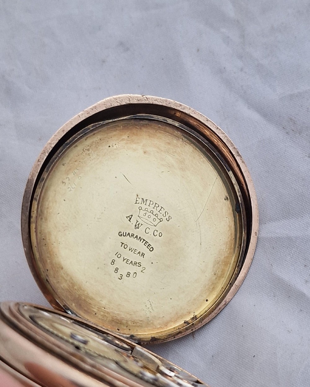 A gold full hunter pocket watch with an open outer case revealing a white enamel dial with black Roman numerals and a subsidiary seconds dial. View II