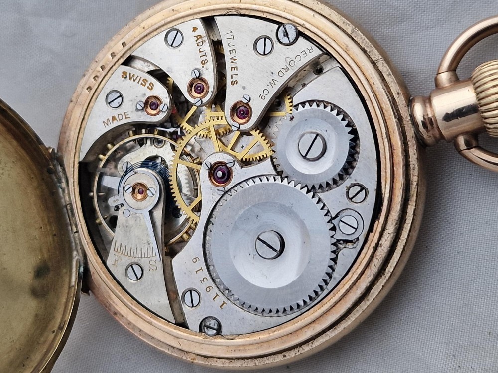 A gold full hunter pocket watch with an open outer case revealing a white enamel dial with black Roman numerals and a subsidiary seconds dial. View IV