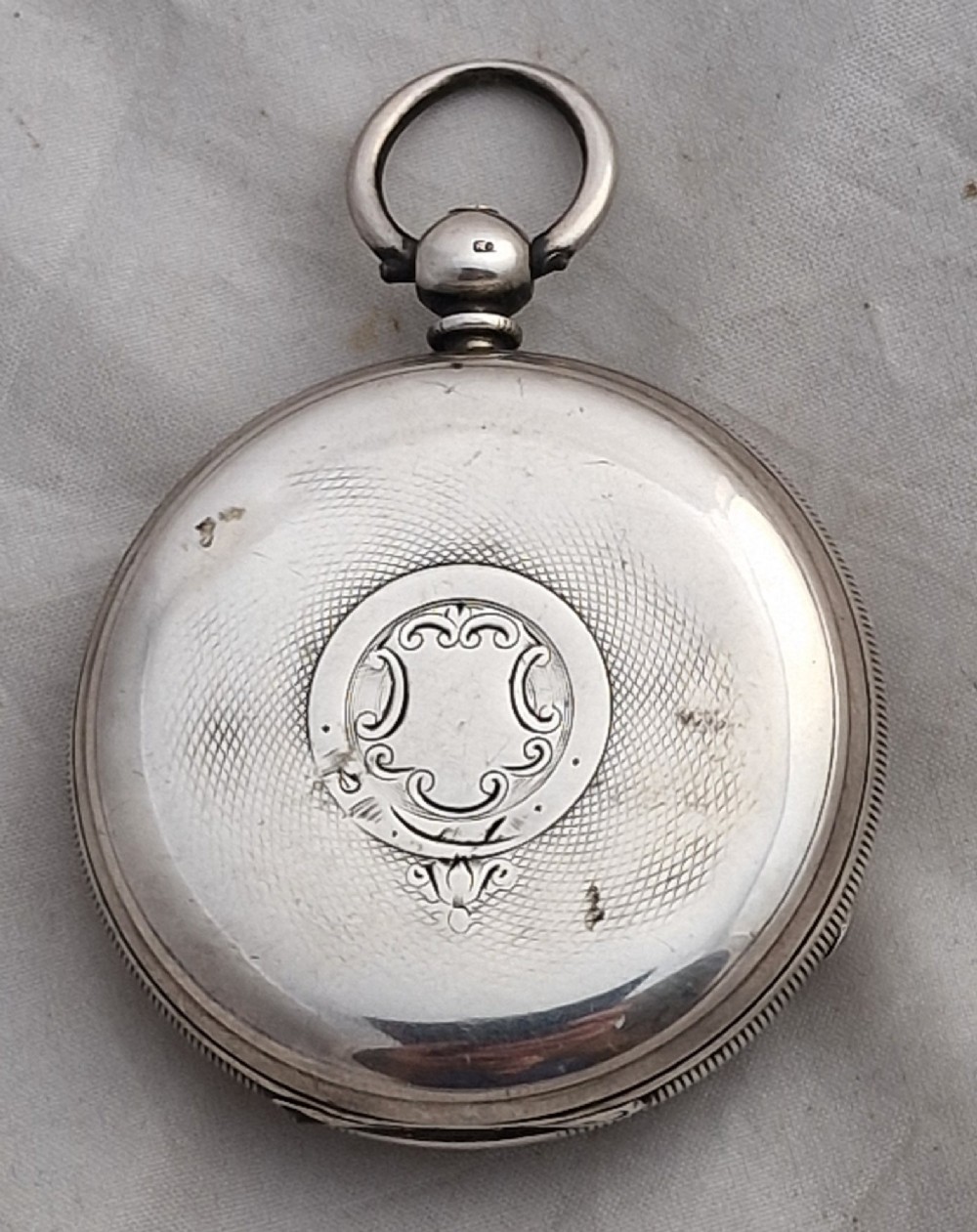 An antique open-face silver pocket watch featuring a white enamel dial with Roman numerals, a subsidiary seconds dial, and an accompanying brass winding key. View II
