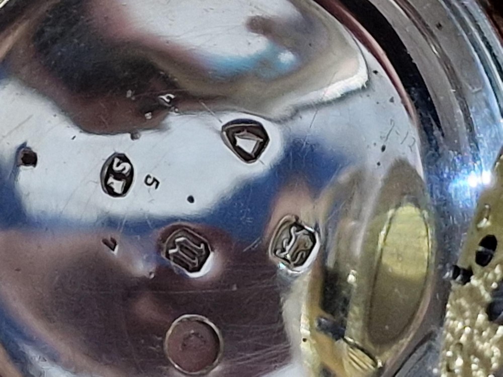 An antique open-face silver pocket watch featuring a white enamel dial with Roman numerals, a subsidiary seconds dial, and an accompanying brass winding key. View III