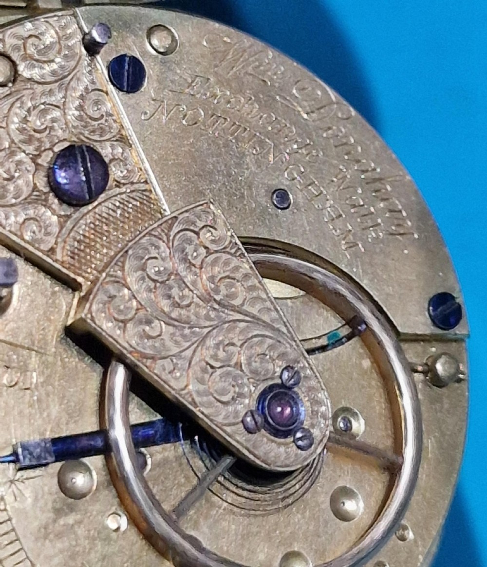 An antique open-face silver pocket watch featuring a white enamel dial with Roman numerals, a subsidiary seconds dial, and an accompanying brass winding key. View IV