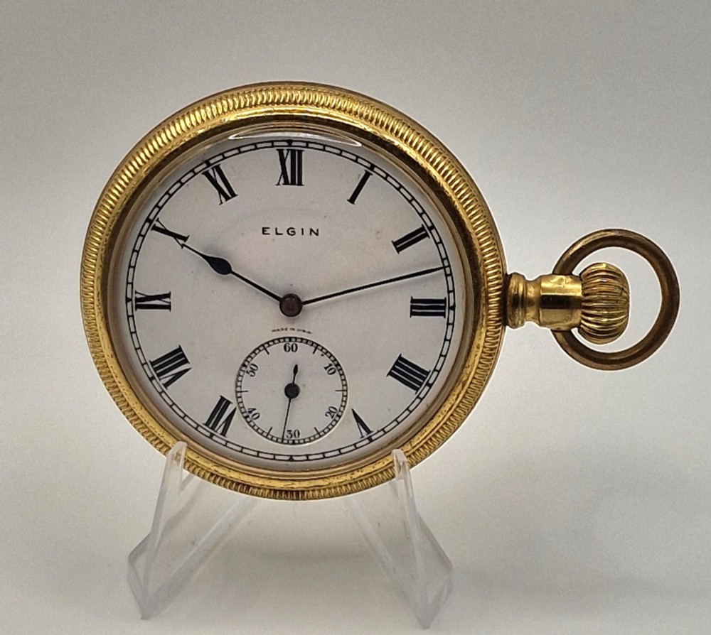 An open face Elgin pocket watch with a textured gold-coloured case, white enamel dial, black Roman numerals, steel hands, and a sub-seconds dial.