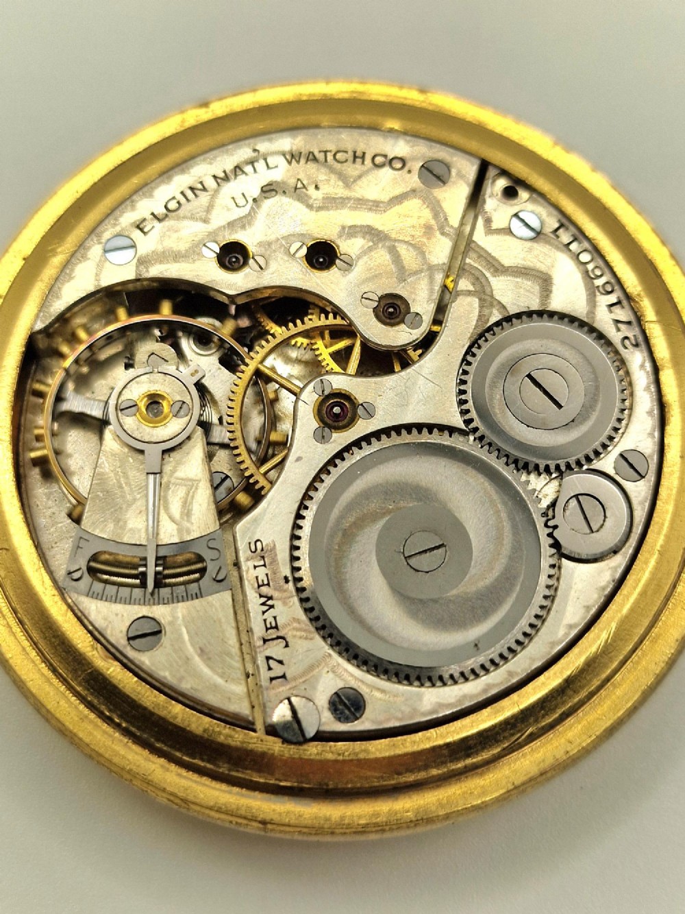An open face Elgin pocket watch with a textured gold-coloured case, white enamel dial, black Roman numerals, steel hands, and a sub-seconds dial. View V