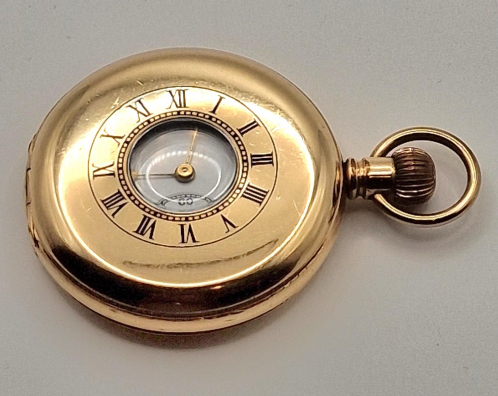 An open gold half hunter pocket watch displaying a white enamel dial with black Roman numerals and a small sub-seconds dial at six oclock. View II