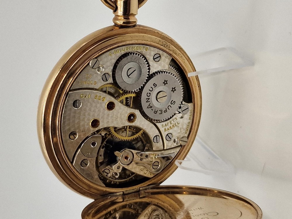 An open gold half hunter pocket watch displaying a white enamel dial with black Roman numerals and a small sub-seconds dial at six oclock. View V