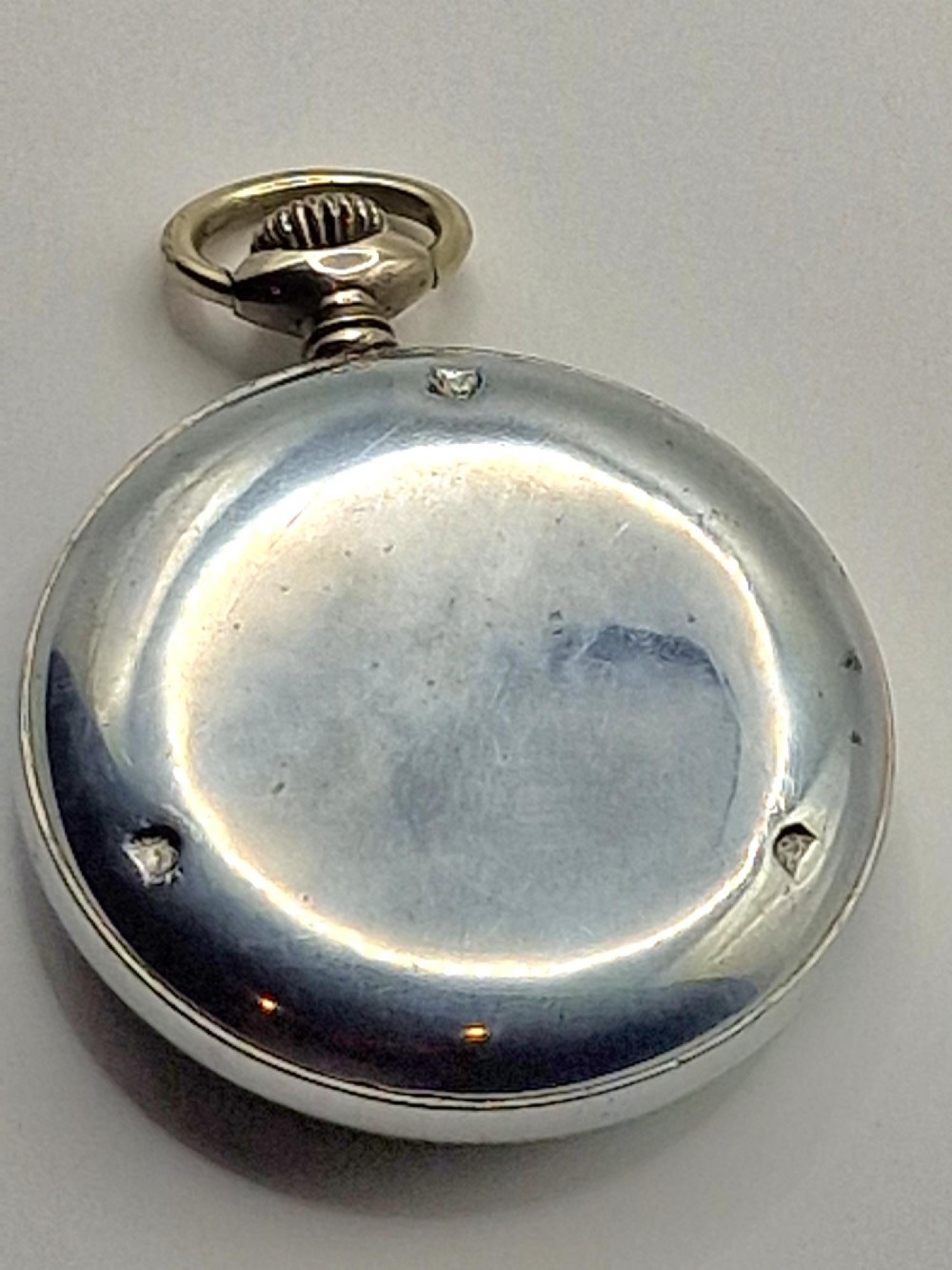 A vintage Grana military pocket watch with a silver-tone case, black dial, luminous Arabic numerals, and subsidiary seconds dial at six oclock. View II