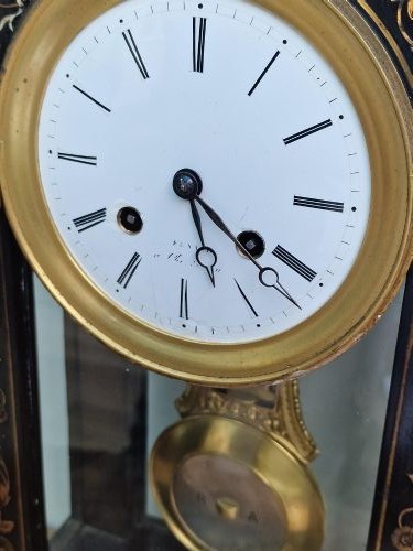 An ebonised wooden mantel clock featuring floral brass and mother of pearl marquetry inlay, an arched glass front displaying a gridiron pendulum, and a white enamel dial with Roman numerals. View III