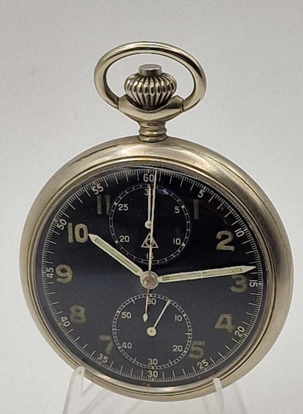 A vintage military chronograph pocket watch featuring a silver-tone metal case, a black dial with luminous Arabic numerals, two sub-dials, and an onion-style crown.